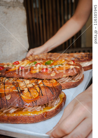 Close-up of a woman holding a tray with traditional cokes fresh from the oven. Vertical 116385945