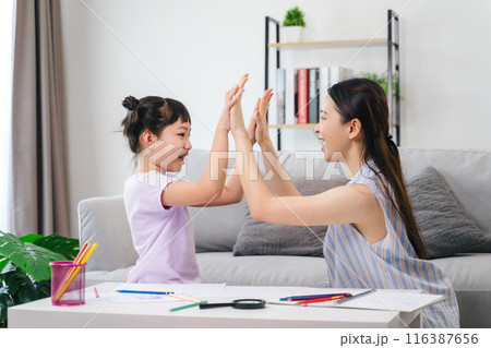 A woman and a child are high five each other in a living room A woman and a child are high five each other in a living room 116387656