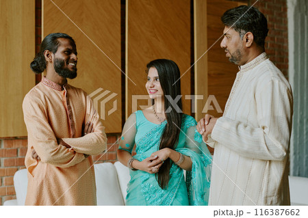 Indian colleagues dressed in patterned clothes smiling while having heated conversation in loft office 116387662