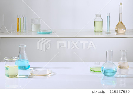 Front angle shot photo on the white background, two tiered shelves in laboratory displaying plenty of experiment glassware, which filled by colorful liquid. Blank space for product presentation Front angle shot photo on the white background, two tiered shelves in laboratory displaying plenty of experiment glassware, which filled by colorful liquid. Blank space for product presentation 116387689
