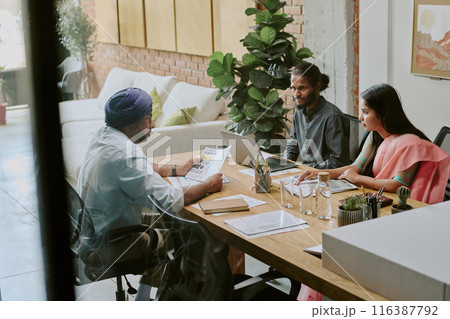 Highly qualified boss holding business documents while holding offline conference with his young staff 116387792
