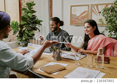 Group of young businessman sitting at wooden table with plans and papers while having heated conversation during offline conference 116387801