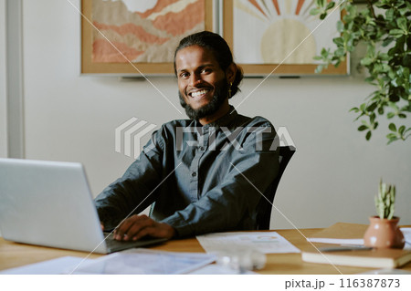 Portrait of Indian IT specialist searching information in Internet while sitting in office 116387873