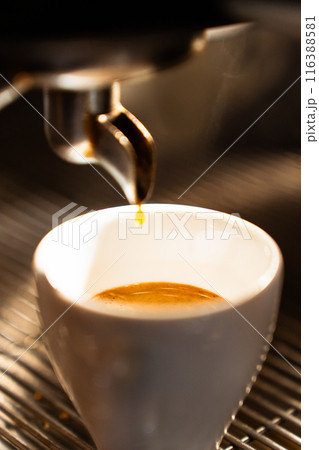Close-up of an espresso cup filled with coffee in the machine. Vertical 116388581