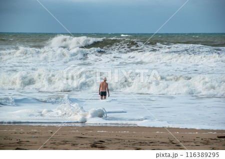 A man alone swims in the Atlantic Ocean in a storm, big waves, danger on the beach 116389295