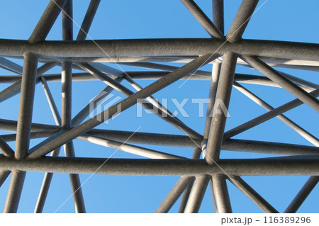 Abstract metal figure on a colorful pink background, artistically welded metal pipes, fragment of scaffolding in NYC 116389296