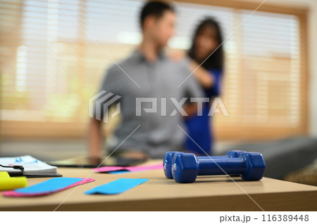 Kinesio tapes and dumbbells on table at physiotherapist office. Rehabilitation, treatment and healthcare concept 116389448