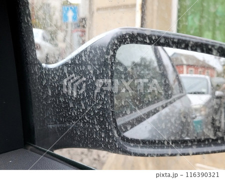 Dirt spattered on the outside of the car window next to the side mirror. Weather phenomena in the urban environment. 116390321