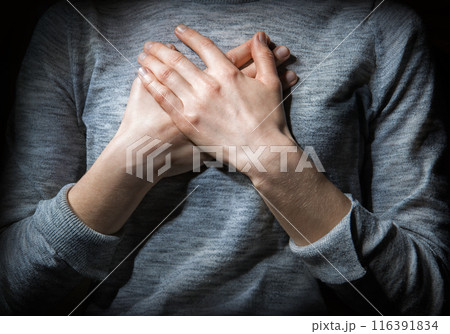 Hands folded in prayer over the heart 116391834