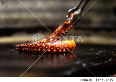 Close-up cooking an octopus tentacle on a restaurant griddle Close-up cooking an octopus tentacle on a restaurant griddle 116393239