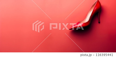 A red high - heeled shoe with a pointed toe, placed against a bright red background with copy space 116395441