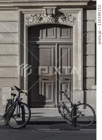 Two bicycle parked at the side of the edge of road in front Traditional french building. 116396152