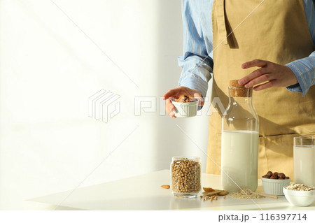 Man, bottle of alternative milk and herbal ingredients on light background, space for text Man, bottle of alternative milk and herbal ingredients on light background, space for text 116397714