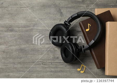 Books with modern headphones, on a gray background. 116397744