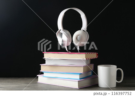Books with modern headphones, on a dark background. 116397752
