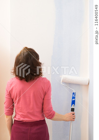 Woman applying paint on wall 116400549