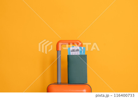 International passport with tickets on an orange suitcase against a yellow background 116400733