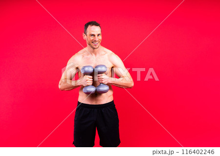 Bodybuilder exercising with dumbbells. Topless young man working out on studio background. 116402246