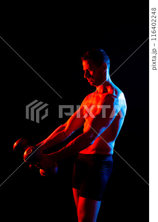 Bodybuilder exercising with dumbbells. Topless young man working out on studio background. Bodybuilder exercising with dumbbells. Topless young man working out on studio background. 116402248