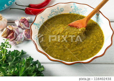 Tkemali sauce, traditional Georgian cuisine, green cherry plum, on a white wooden table, 116402438