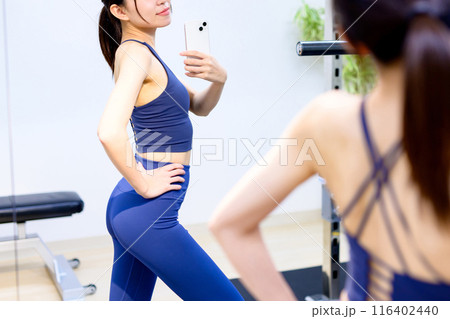 スポーツジムで背中をスマホで撮影する若い女性　パーソナルジム　筋トレ女子　個室 116402440