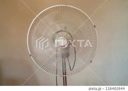 Air fan in the process of blowing and rapid rotation of the blades to cool the room in the summer heat against the background of a beige wall. Devices that help you survive the hot season in comfort. Air fan in the process of blowing and rapid rotation of the blades to cool the room in the summer heat against the background of a beige wall. Devices that help you survive the hot season in comfort. 116402644