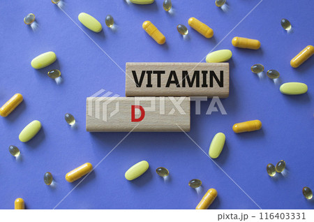 Vitamin D symbol. Concept word Vitamin D on wooden blocks. Beautiful purple background with pills. Medicine and Vitamin D concept. Copy space Vitamin D symbol. Concept word Vitamin D on wooden blocks. Beautiful purple background with pills. Medicine and Vitamin D concept. Copy space 116403331