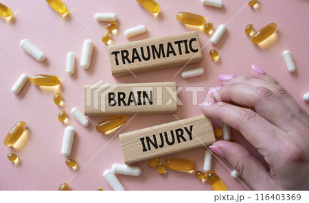 Traumatic Brain Injury symbol. Concept words Traumatic Brain Injury on wooden blocks. Beautiful pink background with pills. Doctor hand. Healthcare and Traumatic Brain Injury concept. Copy space. 116403369