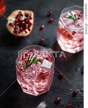 Healthy pomegranate juice with ice in a glass on a dark vintage background close up  116403840
