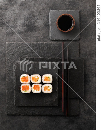 The concept of sushi maki with salmon, cucumber and nori on black slate boards with soy sauce The concept of sushi maki with salmon, cucumber and nori on black slate boards with soy sauce 116403865