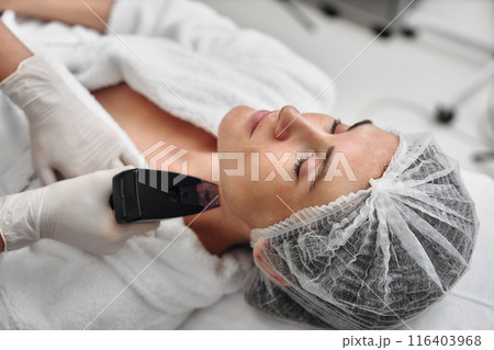 A woman receives Rf-lifting in a beauty salon. 116403968
