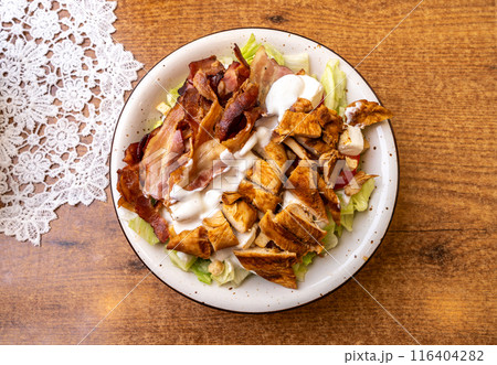 Polish Caesar salad with chicken, bacon and vegetables, high-calorie meat salad with fresh vegetables Polish Caesar salad with chicken, bacon and vegetables, high-calorie meat salad with fresh vegetables 116404282