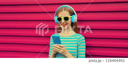 Modern happy young woman listening to music with smartphone, girl smiles in headphones holding phone Modern happy young woman listening to music with smartphone, girl smiles in headphones holding phone 116404991