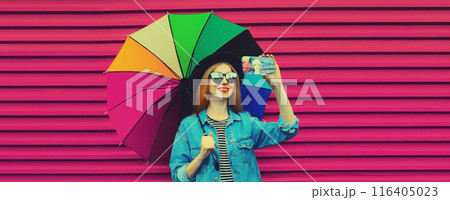 Beautiful happy smiling young woman taking selfie with phone, stylish girl holding colorful umbrella Beautiful happy smiling young woman taking selfie with phone, stylish girl holding colorful umbrella 116405023