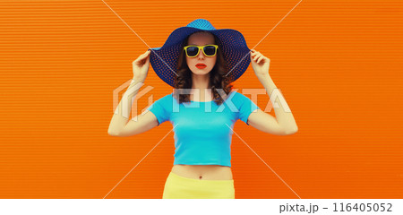 Summer portrait of beautiful stylish young woman posing in hat, glasses on bright orange background 116405052