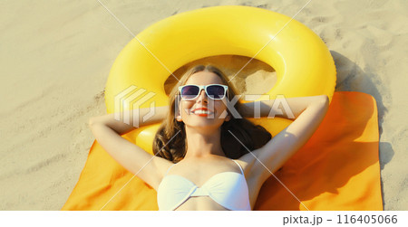 Summer vacation, happy relaxing young woman lying on sand on the beach with swimming inflatable ring Summer vacation, happy relaxing young woman lying on sand on the beach with swimming inflatable ring 116405066