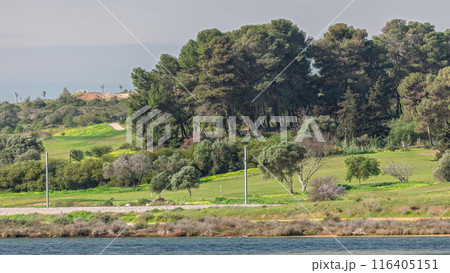 Modern golf courses for tourists with clear ponds and palm trees for relaxation and golf timelapse. Lagos, Portugal, Algarve. 116405151