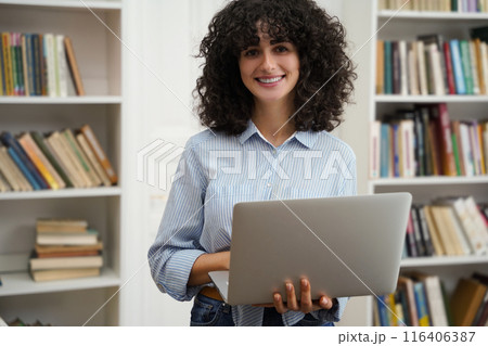 Woman student using laptop computer preparing for exams in college library 116406387