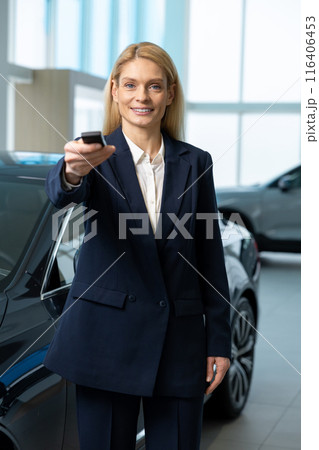 Blonde woman in elegant suit standing near the car with the key 116406453