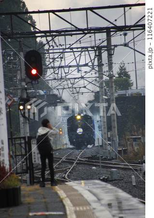 蒸気機関車が激しく蒸気を吐き向ってくる。鉄道ファンはホームの先端まで駆け寄りお出迎え 蒸気機関車が激しく蒸気を吐き向ってくる。鉄道ファンはホームの先端まで駆け寄りお出迎え 116407221