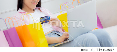 Young asian woman sitting on sofa using laptop computer shopping online with credit card. 116408037