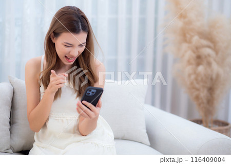 Young asian woman sitting on sofa using smart phone for video call in living room. Young asian woman sitting on sofa using smart phone for video call in living room. 116409004