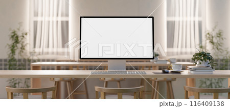 A computer with a white-screen mockup on a wood table in a minimalist Scandinavian co working space. 116409138