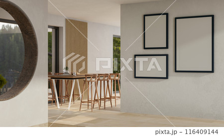 A modern spacious indoor corridor with a table with stools, and frames mockup on the wall. 116409144