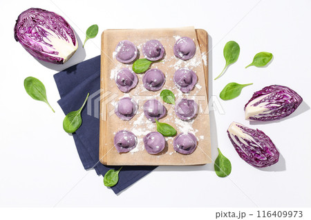 Purple dumplings on kitchen board, basil and cabbage on white background, top view Purple dumplings on kitchen board, basil and cabbage on white background, top view 116409973