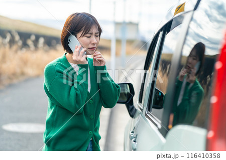 車のトラブルで電話する女性 自動車事故で困る女性 車のトラブルで電話する女性 自動車事故で困る女性 116410358