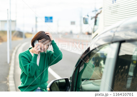 車のトラブルで電話する女性 自動車事故で困る女性 車のトラブルで電話する女性 自動車事故で困る女性 116410701