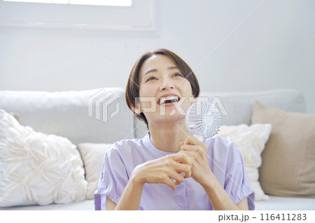 リビングで携帯扇風機を使う女性 116411283