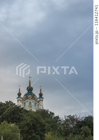 Saint Andrew church in Kyiv. Kyiv famous landmark. Religious architecture. Ortodox cathedral in cloudy day. St.Andrew cathedral with cross on summer landscape background. 116412741