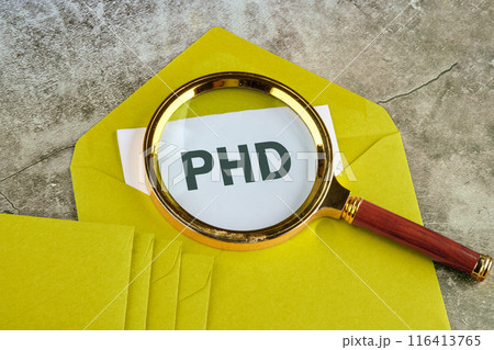 PhD Doctor of Philosophy Degree Education Graduation. PHD word through a magnifying glass on a piece of mustard-colored envelope PhD Doctor of Philosophy Degree Education Graduation. PHD word through a magnifying glass on a piece of mustard-colored envelope 116413765
